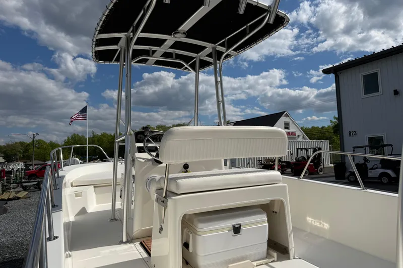 Slide: The Image of 2018 Boston Whaler 210 Montauk boat with T-top, docked under a partly cloudy sky. - 7
