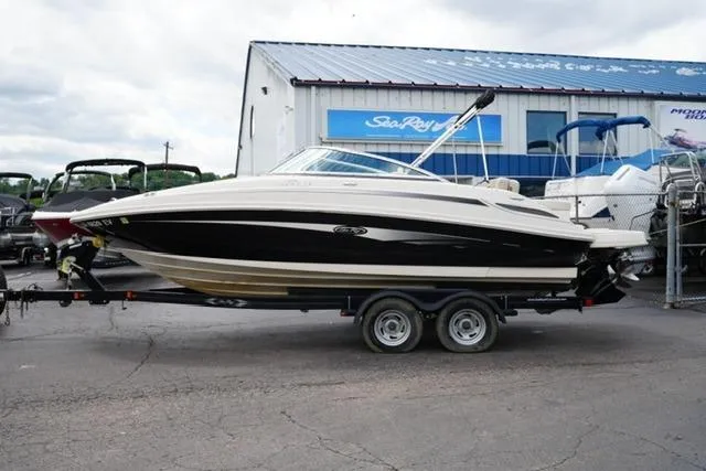 The Image of 2010 Sea Ray 220 Sundeck boat on trailer, parked outside dealership. - 1