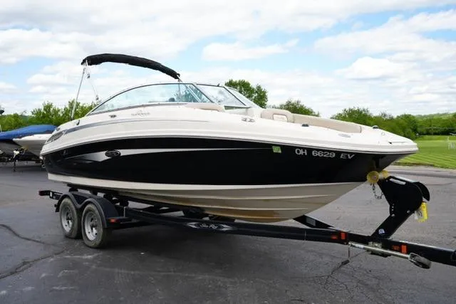 Slide: The Image of 2010 Sea Ray 220 Sundeck boat on trailer, parked outdoors under a cloudy sky. - 3