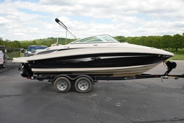 Slide: The Image of 2010 Sea Ray 220 Sundeck boat on trailer, parked outdoors under cloudy sky. - 4
