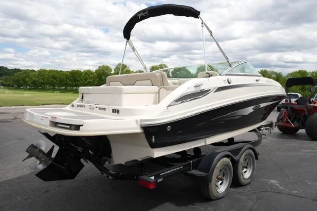 Slide: The Image of 2010 Sea Ray 220 Sundeck boat on trailer, parked outdoors under cloudy sky. - 5
