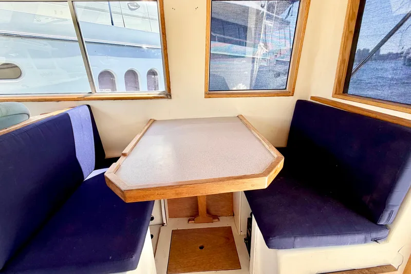 Slide: The Image of 1970 Bertram boat interior with blue cushioned seating and wooden table. - 11