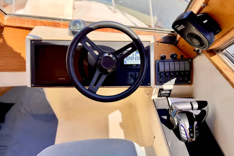 Slide: The Image of 1970 Bertram boat helm with steering wheel, Garmin display, and control panel. - 13