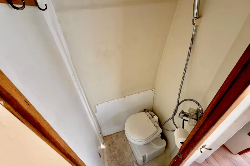 Slide: The Image of Compact 1970 Bertram boat bathroom with toilet and showerhead. - 15