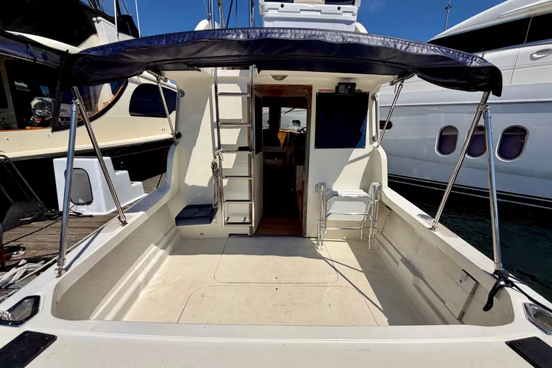 Slide: The Image of 1970 Bertram boat with open deck, canopy, and ladder, docked between yachts. - 16