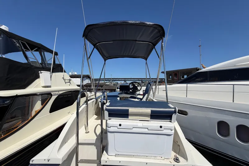 Slide: The Image of 1970 Bertram boat docked between two yachts under clear blue sky. - 17