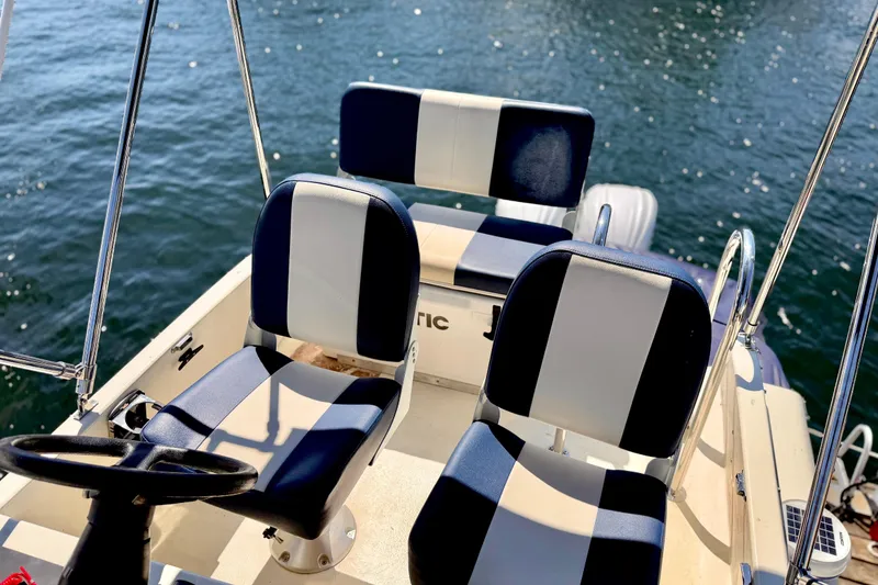 Slide: The Image of 1970 Bertram boat interior with striped seats and steering wheel on water. - 18