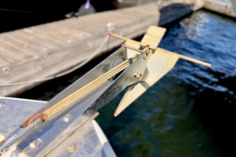 Slide: The Image of 1970 Bertram boat anchor detail at dockside, with water and wooden dock in background. - 23