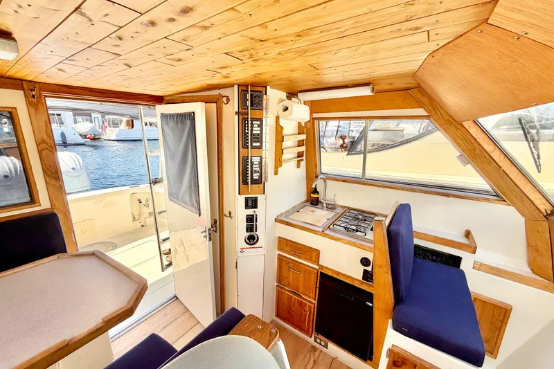 Slide: The Image of Interior of a 1970 Bertram boat with wooden paneling and compact kitchen area. - 9