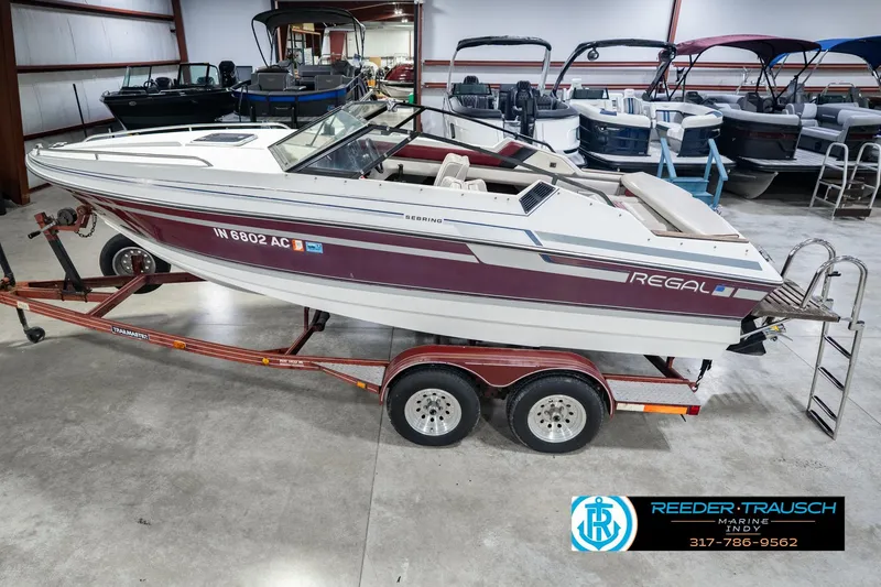 The Image of 1986 Regal Sebring 195 boat on trailer in showroom with other boats. - 0