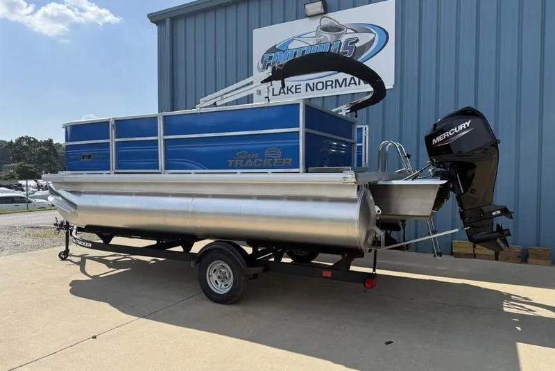Slide: The Image of 2026 Sun Tracker Party Barge 16 DLX pontoon boat with Mercury engine, parked outside. - 4