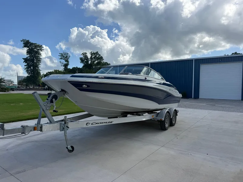 The Image of 2022 Crownline Eclipse E215 XS boat on trailer, parked outdoors. - 1