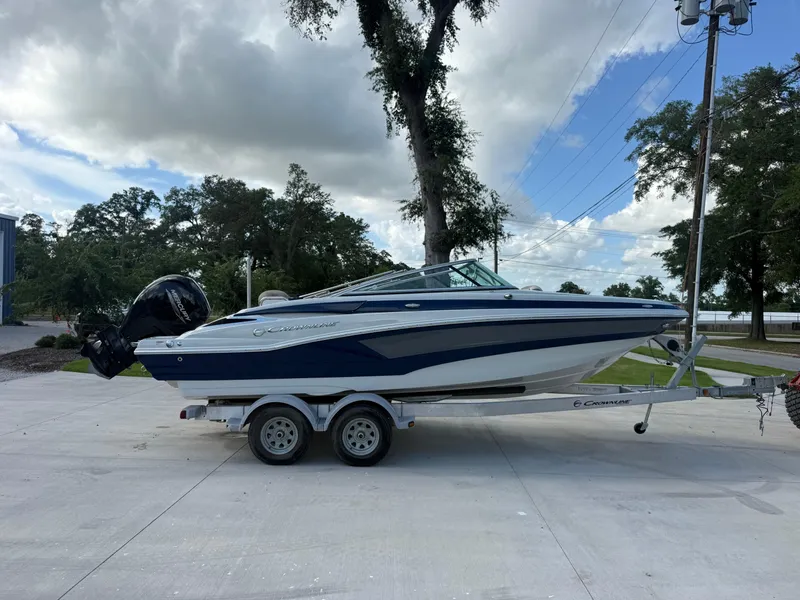 Slide: The Image of 2022 Crownline Eclipse E215 XS boat on trailer, parked outdoors under cloudy sky. - 3