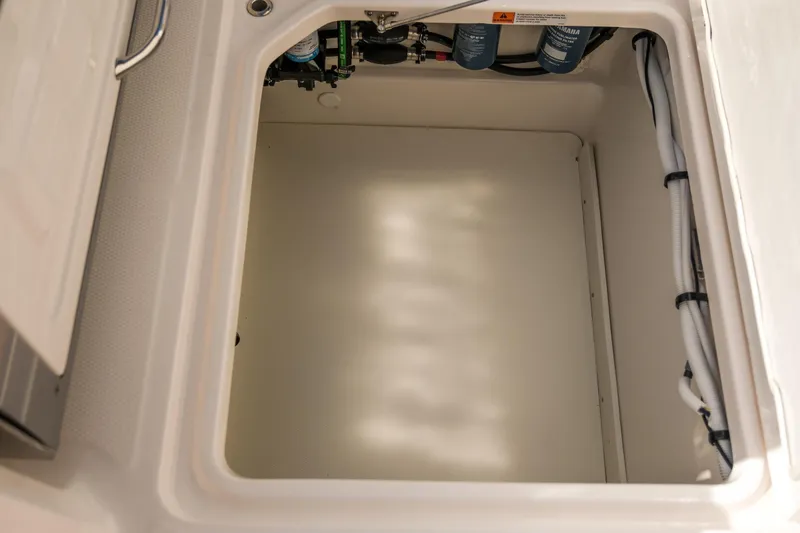 Slide: The Image of 2025 Robalo R300 Center Console storage compartment with visible wiring and filters. - 15