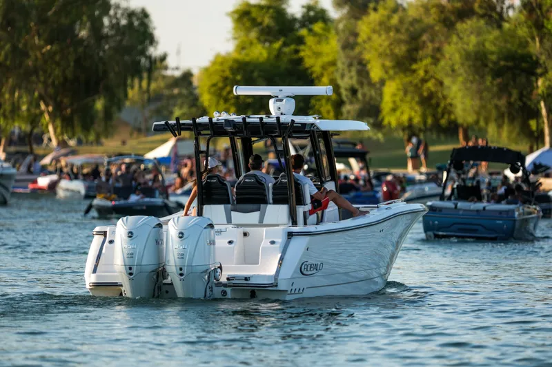 Slide: The Image of 2025 Robalo R300 Center Console boat cruising on a busy lake with people. - 18