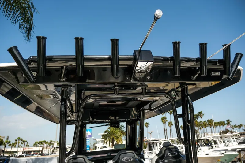 Slide: The Image of 2025 Robalo R300 Center Console boat with rod holders and canopy, docked under clear sky. - 39