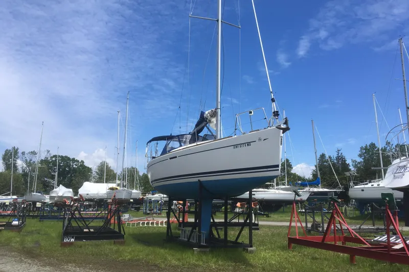 Slide: The Image of 2004 Dufour 34 Performance sailboat on stands in a boatyard under a clear blue sky. - 12
