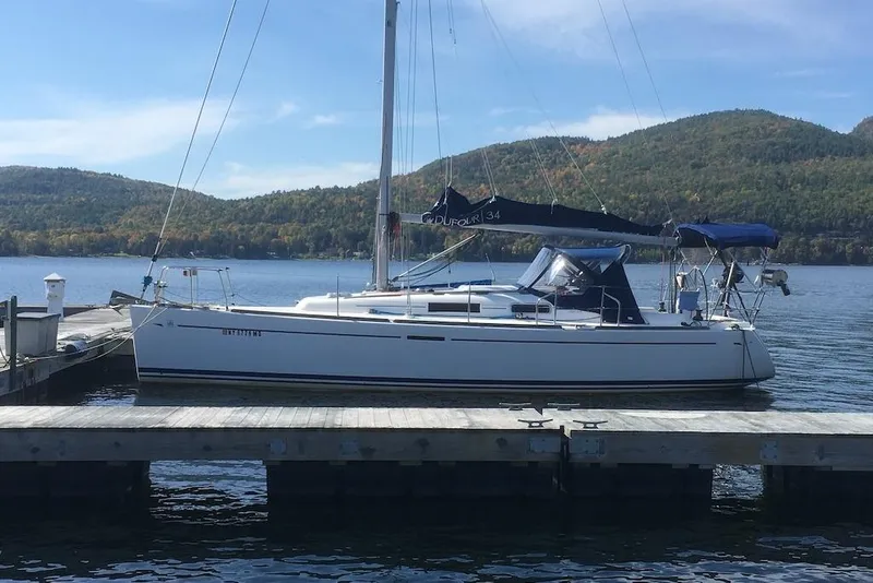 Slide: The Image of Sailboat Dufour 34 Performance 2004 docked on a serene lake with scenic mountain backdrop. - 2