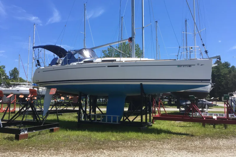 Slide: The Image of 2004 Dufour 34 Performance sailboat on stands in a marina under a clear blue sky. - 6