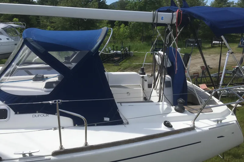 Slide: The Image of 2004 Dufour 34 Performance sailboat with blue canopy, docked outdoors. - 8