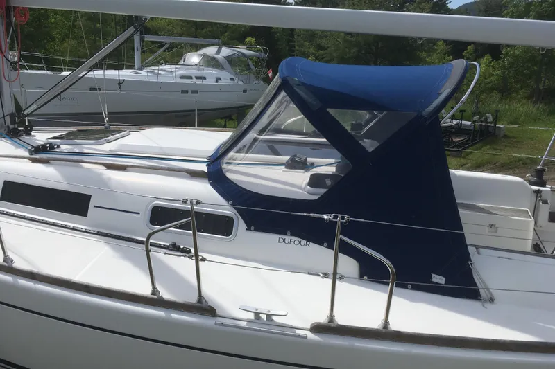 Slide: The Image of 2004 Dufour 34 Performance sailboat with blue canopy, docked outdoors. - 9