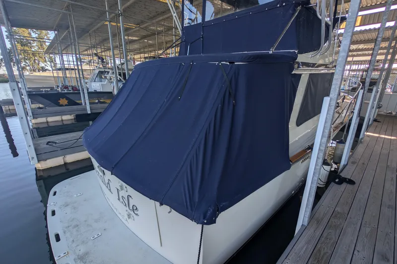 Slide: The Image of 1975 Tollycraft 37 Sedan docked, covered with navy blue canvas, in a marina setting. - 14
