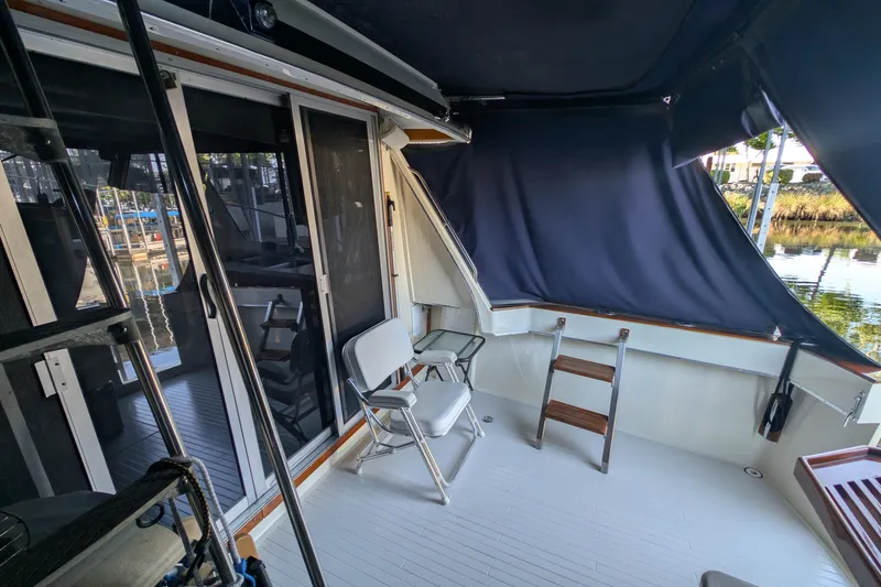 Slide: The Image of 1975 Tollycraft 37 Sedan boat interior with seating and ladder, docked by the water. - 16