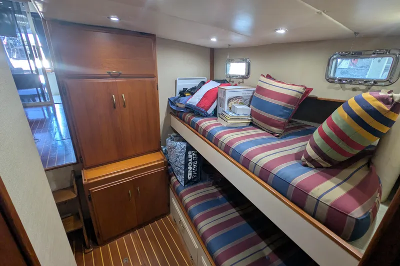Slide: The Image of 1975 Tollycraft 37 Sedan cabin with striped cushions, wooden cabinets, and porthole windows. - 41