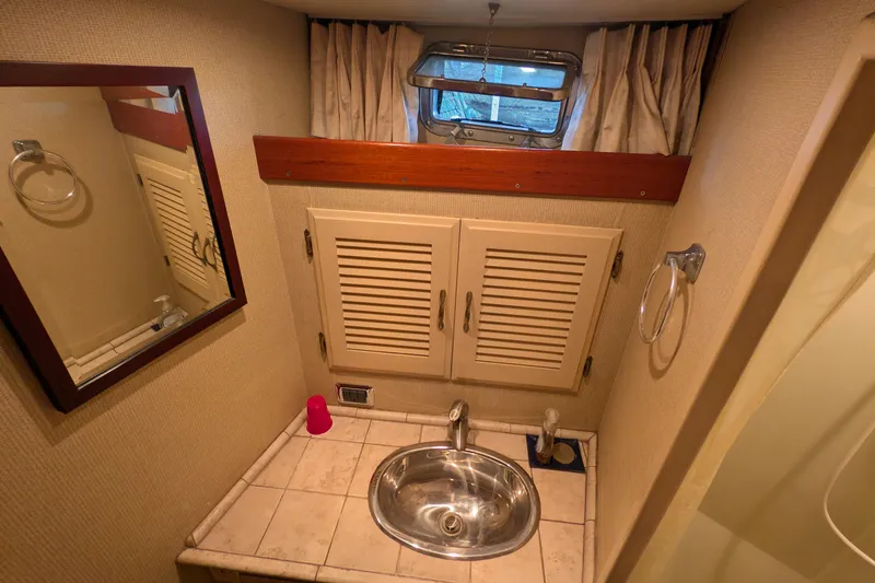 Slide: The Image of 1975 Tollycraft 37 Sedan bathroom with sink, mirror, and storage cabinets. - 47