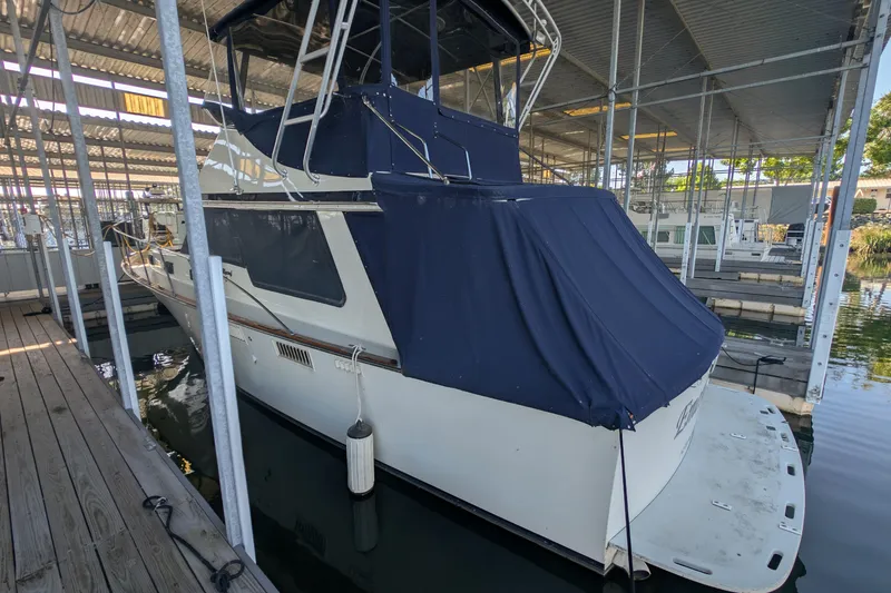 Slide: The Image of 1975 Tollycraft 37 Sedan docked under a covered marina, featuring a blue canvas cover. - 8