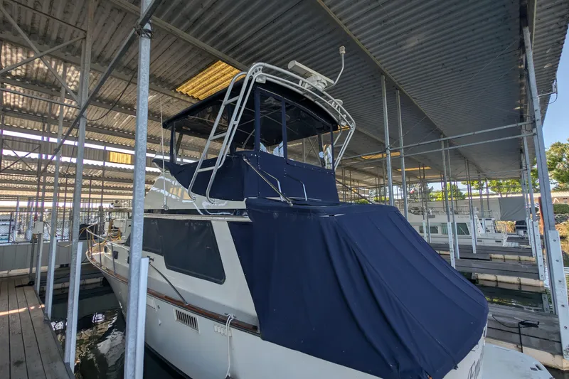 Slide: The Image of 1975 Tollycraft 37 Sedan yacht docked in a covered marina, featuring a blue canopy. - 9