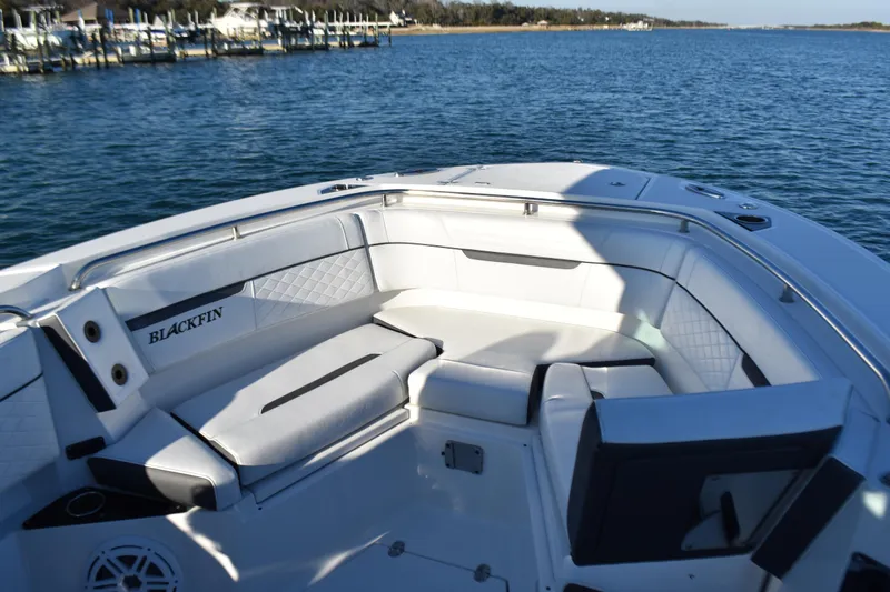 Slide: The Image of 2022 Blackfin 272 CC boat interior with white seating, docked by the water. - 11