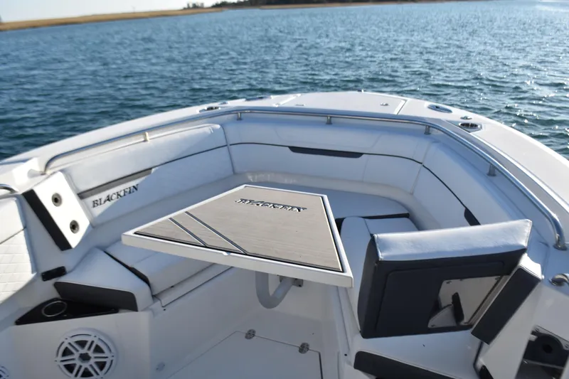 Slide: The Image of 2022 Blackfin 272 CC boat interior with seating and table on calm water. - 12