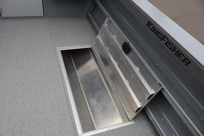 Slide: The Image of 2026 KingFisher 2825 Coastal Express boat with open storage compartment on textured deck. - 11