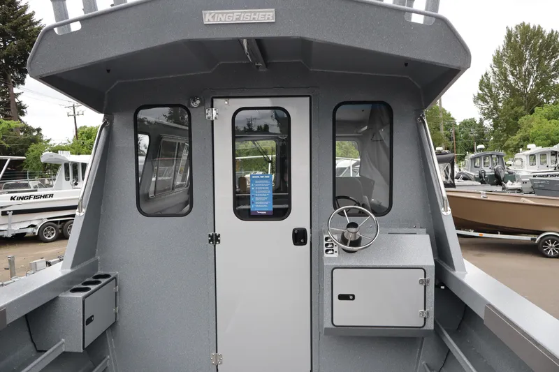 Slide: The Image of 2026 KingFisher 2825 Coastal Express boat exterior with steering wheel and cabin door. - 14