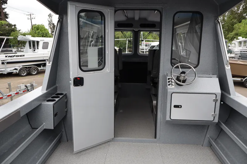 Slide: The Image of 2026 KingFisher 2825 Coastal Express boat interior with steering wheel and open cabin door. - 19