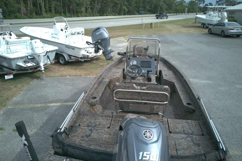 Slide: The Image of 2024 Xpress H20B Bay boat with Yamaha engine, parked near other boats and vehicles. - 10