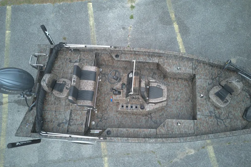 Slide: The Image of 2024 Xpress H20B Bay boat, aerial view, camo design, parked on asphalt. - 7