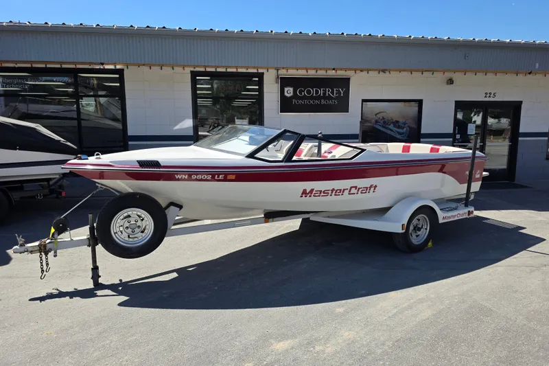 The Image of 1987 MasterCraft ProStar 190 boat on trailer outside dealership. - 0