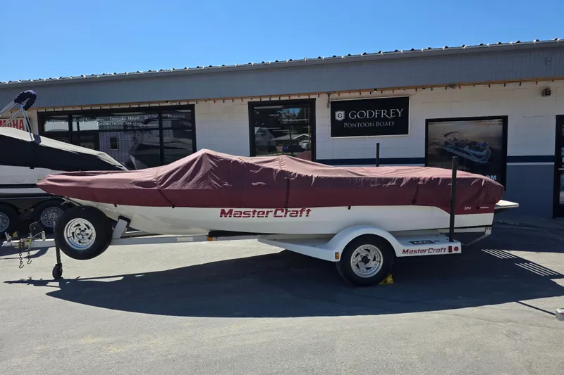 Slide: The Image of 1987 MasterCraft ProStar 190 boat covered, parked outside Godfrey Pontoon Boats dealership. - 2