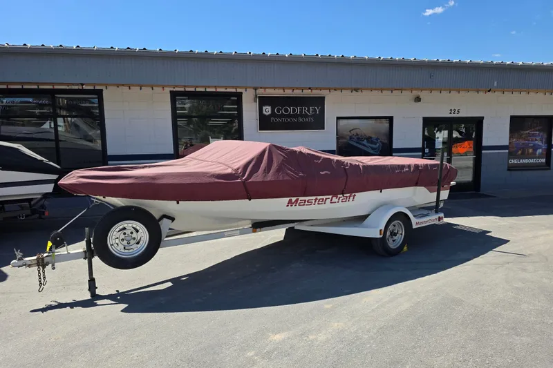 Slide: The Image of 1987 MasterCraft ProStar 190 boat on trailer, covered, outside dealership. - 3