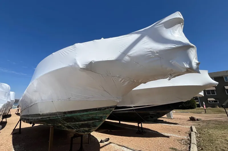The Image of 1994 Sea Ray 310 Amberjack boat covered in protective white shrink wrap on a sunny day. - 1