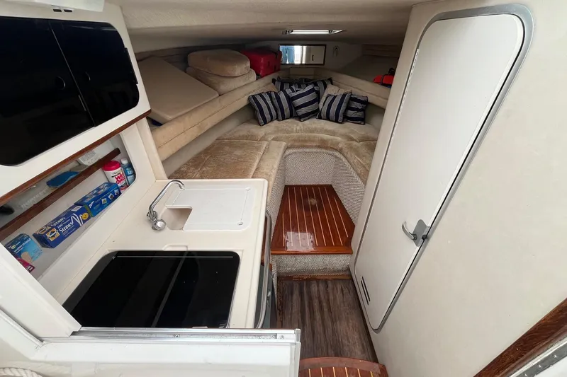 Slide: The Image of Interior of a 1994 Sea Ray 310 Amberjack boat with cozy seating and compact kitchenette. - 16