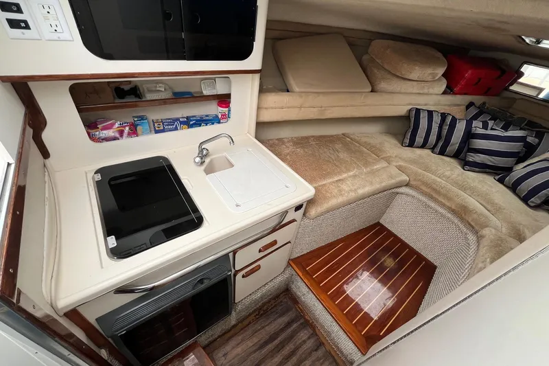 Slide: The Image of 1994 Sea Ray 310 Amberjack cabin interior with kitchenette and cozy seating area. - 17