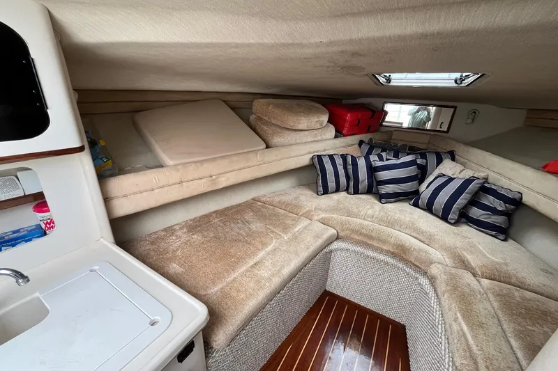 Slide: The Image of Interior of 1994 Sea Ray 310 Amberjack boat with cozy seating and striped cushions. - 18