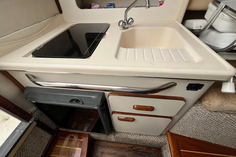 Slide: The Image of 1994 Sea Ray 310 Amberjack boat kitchen with sink, stove, and storage cabinets. - 19