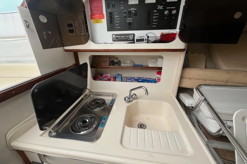 Slide: The Image of 1994 Sea Ray 310 Amberjack boat kitchen with stove, sink, and control panel. - 22