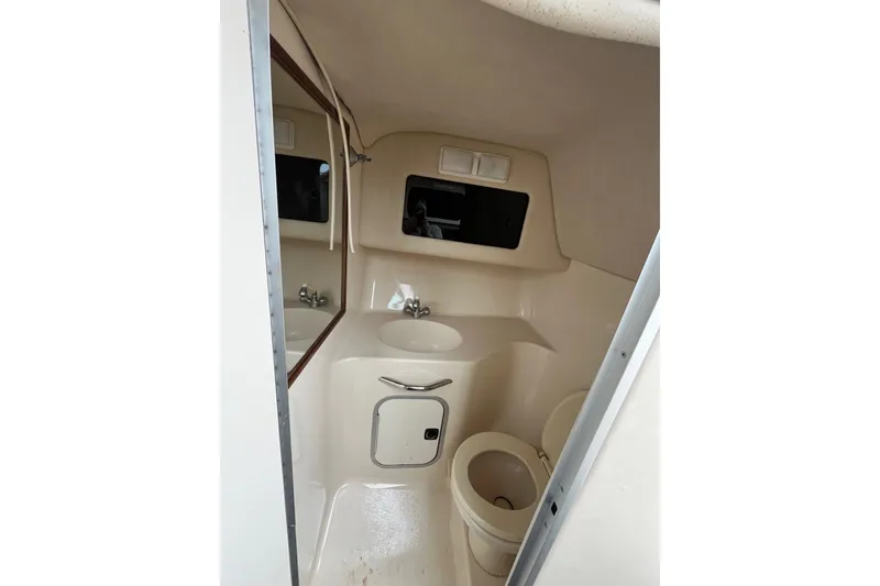 Slide: The Image of 1994 Sea Ray 310 Amberjack boat bathroom with sink, mirror, and toilet. - 28