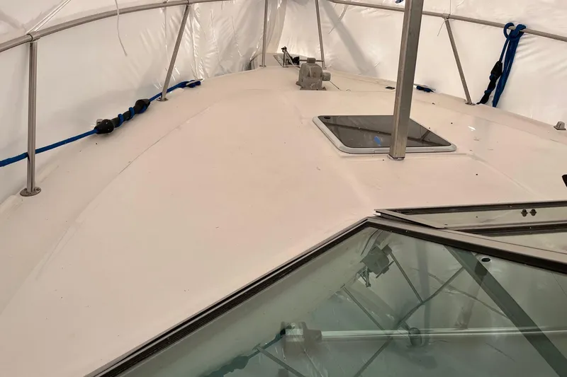 Slide: The Image of 1994 Sea Ray 310 Amberjack boat deck under protective cover, featuring hatch and railing. - 31
