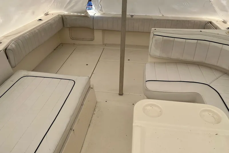 Slide: The Image of 1994 Sea Ray 310 Amberjack boat interior with white cushioned seating and table. - 8